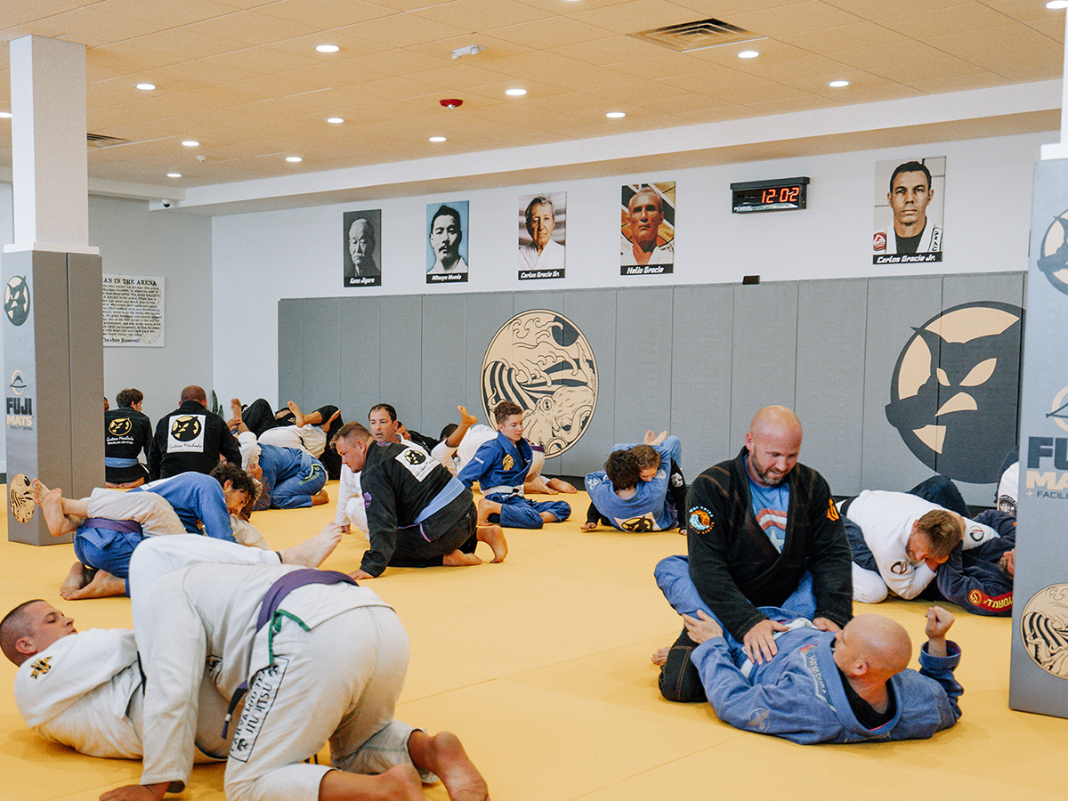 Wide view of Gustavo Machado Academy, where pairs of students are spread out and train Brazilian Jiu-Jitsu moves across the mat.