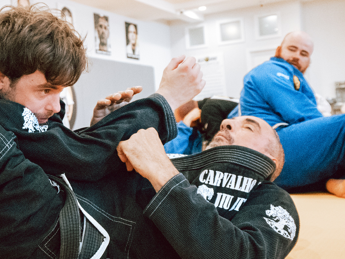 Two Brazilian Jiu-Jitsu students caught in a move on the mat at Gustavo Machado Academy.
